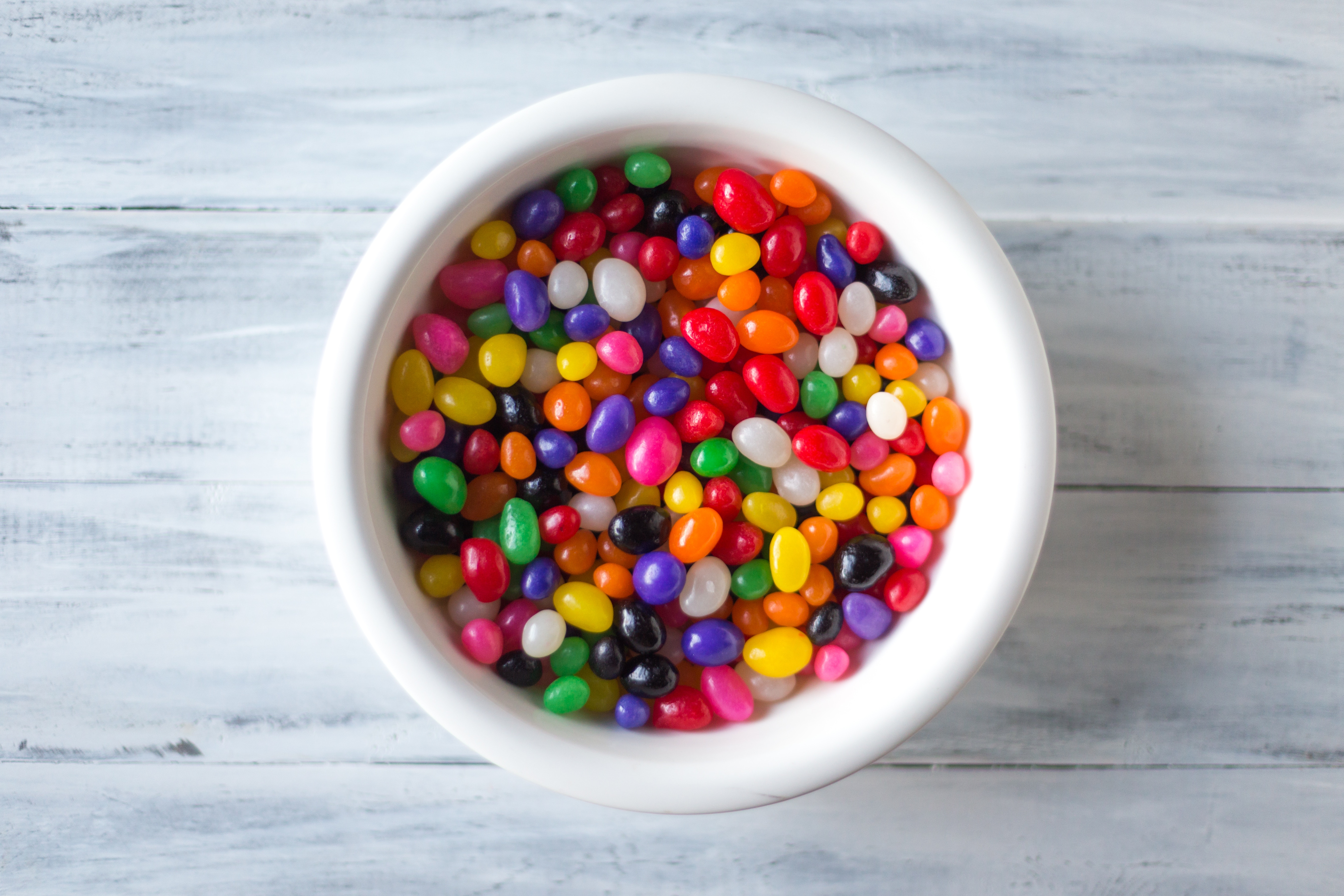A picture of a bowl with jelly beans on a marble background. 