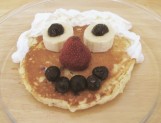 A picture of a pancake with fruit to make mouth, nose, and eyes. Whipped cream to make the hair. 