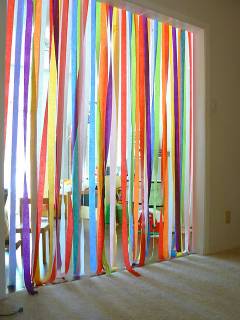 An image of crepe paper strung from the top of a doorway and just touching the floor. Various colors. Everybody walking through this door way would have to go through crepe streamers. 