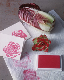 A picture of bunched cabbage, red ink, and paper with cabbage ink stamps. Showing how you can use the fruits and vegetables to create beautiful art. 