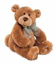 A picture of a stuffed, brown teddy bear sitting on the ground with a white background. 