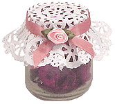 A baby jar turned into a decorative Potpourri jar. A white doily and pink ribbon on top of the jar. 