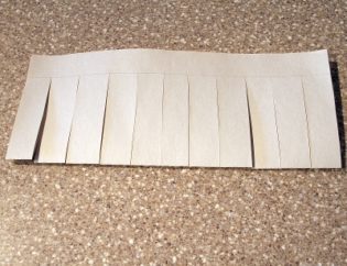 A picture of a piece of paper with evenly cut slits across it. The beginning stages of a Chinese lantern craft. 