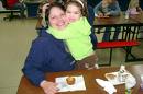 A picture of a daughter hugging her mom and a muffin in front depicting muffins for mom school event. 