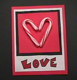 Two candy canes used to form a heart on a card that says "love". 