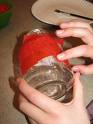 An image of a hand putting red covering on a baby food jar with the intentions of turning it into a candle. 