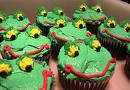 Green cupcakes that are decorated to look like frogs. 