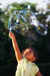 A child making large bubbles outside. 