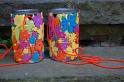 A picture of decorated tin cans with strings to be put on kids feet to be used as stilts. 