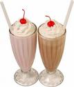 An image of two milkshakes next to each other with whipped cream and cherries on top. 