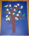 An art project where popcorn represents a cherry blossom. A brown tree, green leaves, and popcorn cherry blossoms with a blue background. 