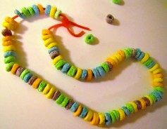 A picture of a necklace made from Fruit Loops cereal on a red string. 