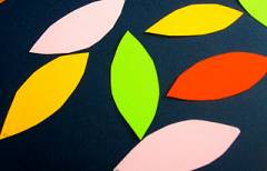 An image of construction paper leaf cutouts. Pink, green, red, and yellow. 