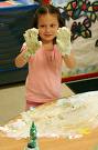 A picture of a young girl holding her hands in front of her with shaving cream covering her hands. 