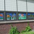 A picture of painted windows on the outside of a industrial building. 4 different designs. 
