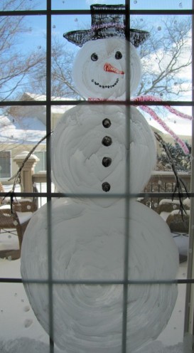 A picture of a large snowman painted on a window. 