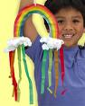 A picture of a child holding a crafted rainbow with the rainbow having a cloud at each end. 