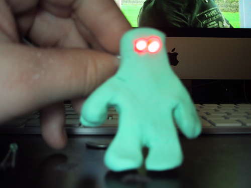 A picture of gumby made out of clay with red eyes. 