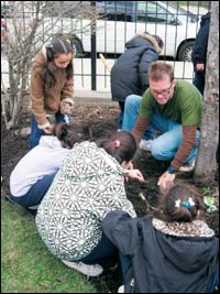 A picture of a teacher and several kids planting bulbs in the fall. 