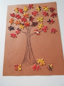 A picture of a puzzle leaf tree. The trunk and branches are drawn and the puzzle pieces are painted orange, red, and yellow and used as leaves. 