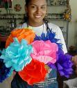 An image of tissue paper turned into flowers. A lady holding a large bouquet of them. 