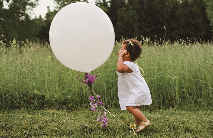 baby playing with a big white balloon
